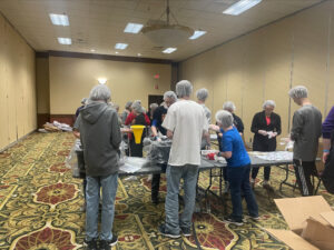 A group of teen volunteers packing food as an example of a faith activity for youth at a Quake event. 